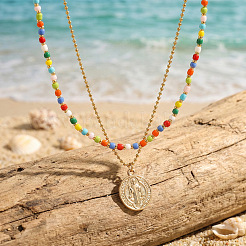Boho-Halskette aus farbenfrohen Glasperlen in Doppelreihen mit Anhänger aus Edelstahl in Form einer Heiligen-Benedikt-Medaille.&nbsp;OL9548-1